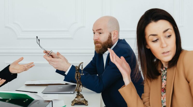 Three adults in a heated discussion with legal documents, indoors.