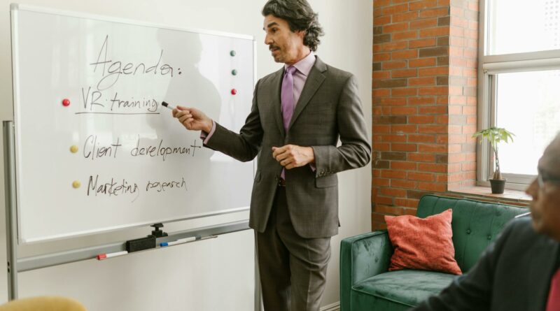 Businessman presenting a whiteboard agenda on VR training in modern office meeting.