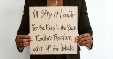 Person holding a sign promoting anti-racism message with emphasis on social justice.