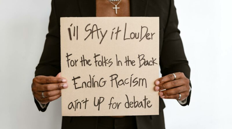 Person holding a sign promoting anti-racism message with emphasis on social justice.