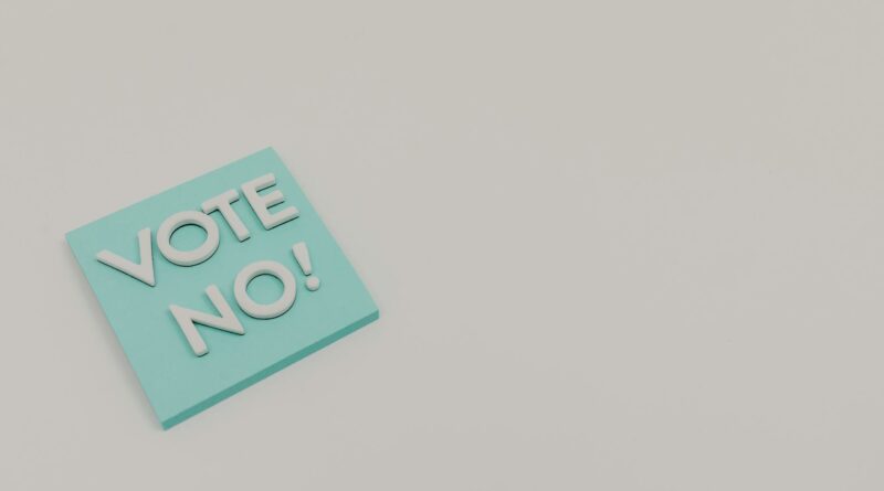 A blue sticky note displaying the message 'Vote No!' on a white surface, minimalistic and impactful.