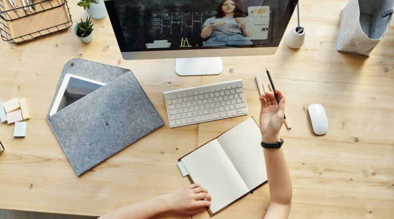 Teen girl actively learning in an organized home workspace via online class on a desktop computer.