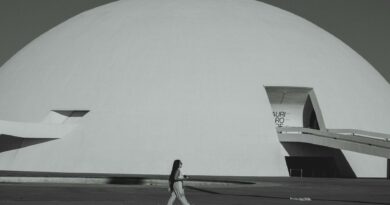 A woman walks by the futuristic Niemeyer Dome in Brasília, showcasing modern architecture.