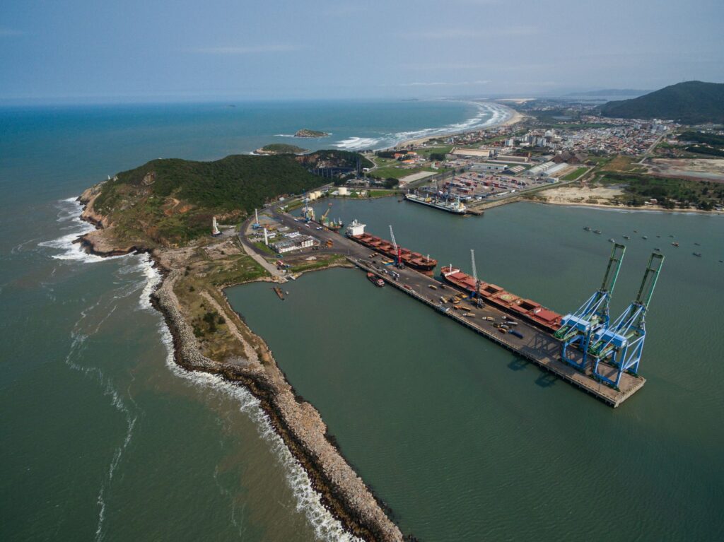 Caminhões e navios em um porto brasileiro, simbolizando a infraestrutura logística do país