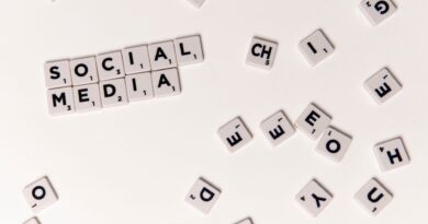 Mãos segurando um smartphone com ícones de redes sociais, sobreposto por uma balança simbolizando o equilíbrio entre liberdade de expressão e regulação.