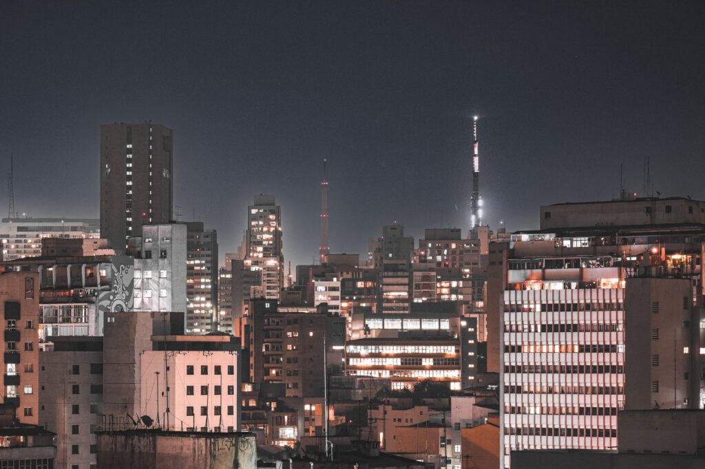 Vista aérea da cidade de São Paulo com luzes de viaturas policiais ao fundo, simbolizando a investigação do crime organizado.