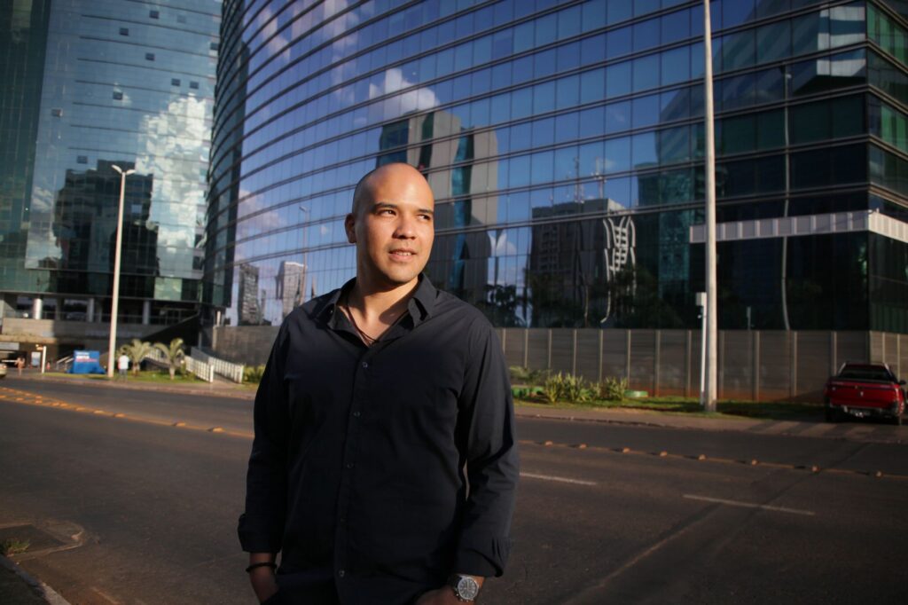 Mãos de empresários apertando-se sobre uma mesa com documentos e um gráfico de crescimento, simbolizando confiança e parceria em um ambiente de compliance.