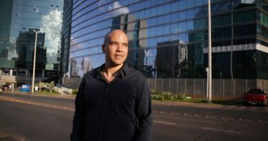 Mãos de empresários apertando-se sobre uma mesa com documentos e um gráfico de crescimento, simbolizando confiança e parceria em um ambiente de compliance.