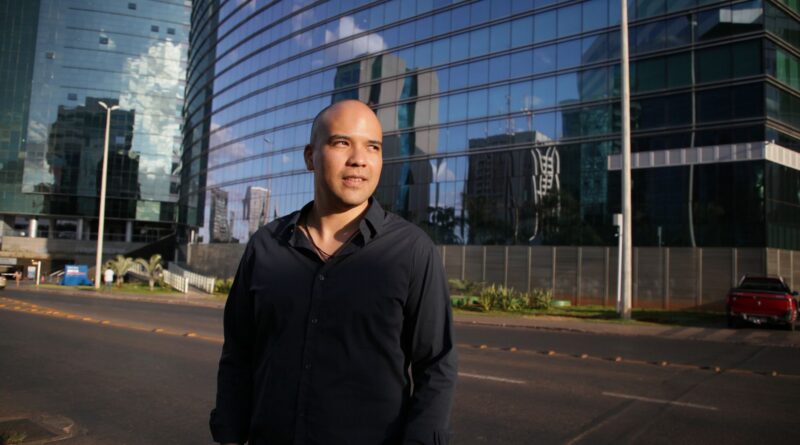 Mãos de empresários apertando-se sobre uma mesa com documentos e um gráfico de crescimento, simbolizando confiança e parceria em um ambiente de compliance.