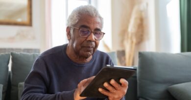 Idoso utilizando um tablet com auxílio, simbolizando a inclusão digital e o aprendizado de novas tecnologias.