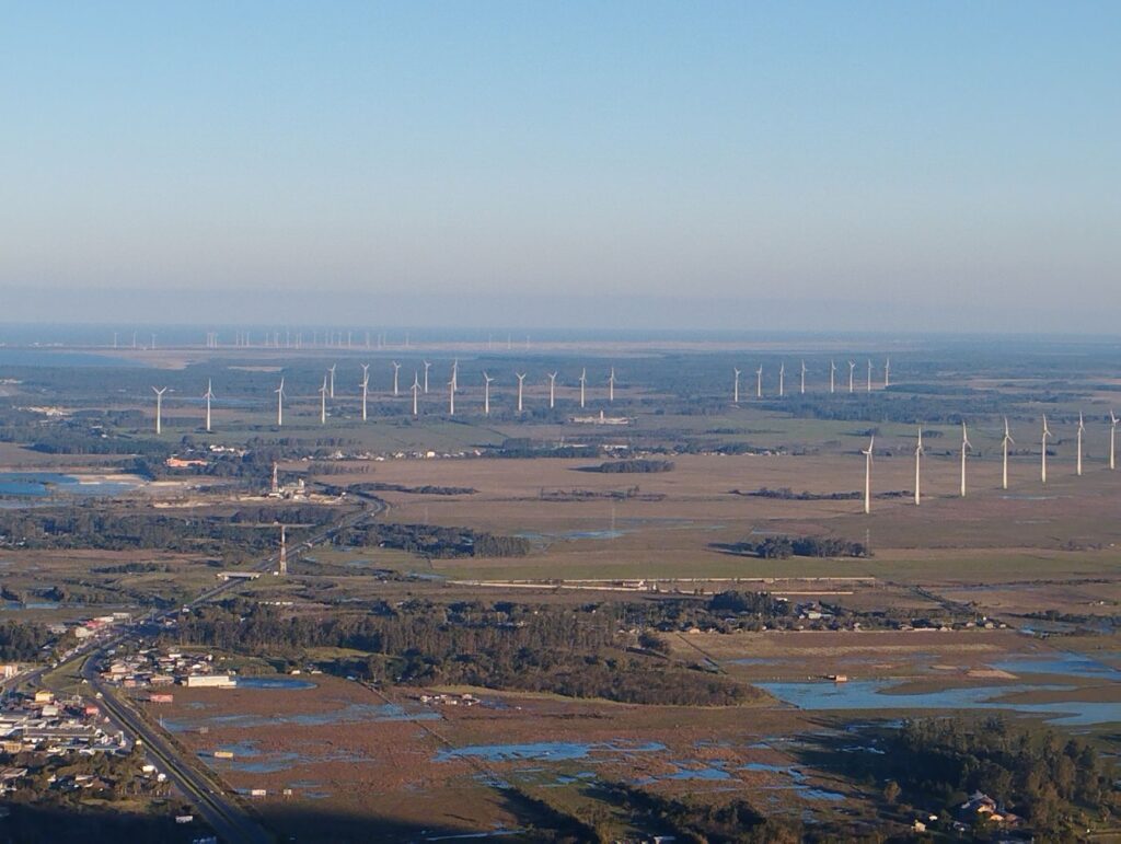 Avião decolando com rastro de fumaça limpa sobre campos de cana-de-açúcar, simbolizando a produção de SAF no Brasil.