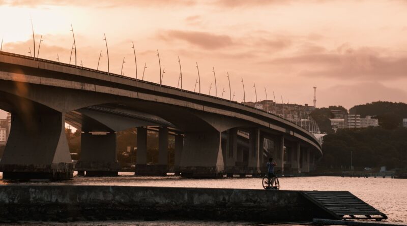 Vista aérea de uma grande obra de infraestrutura no Brasil, como uma ponte moderna ou um trecho de rodovia em construção, simbolizando o desafio e o potencial de desenvolvimento.