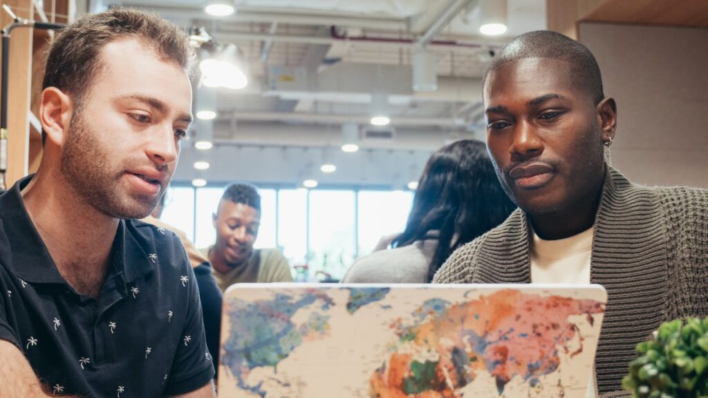 Equipe de startup brasileira trabalhando em expansão global, com mapa-múndi ao fundo
