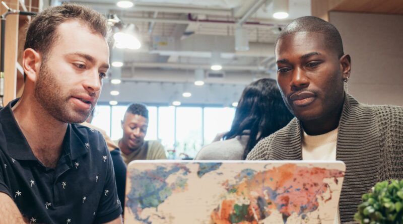 Equipe de startup brasileira trabalhando em expansão global, com mapa-múndi ao fundo