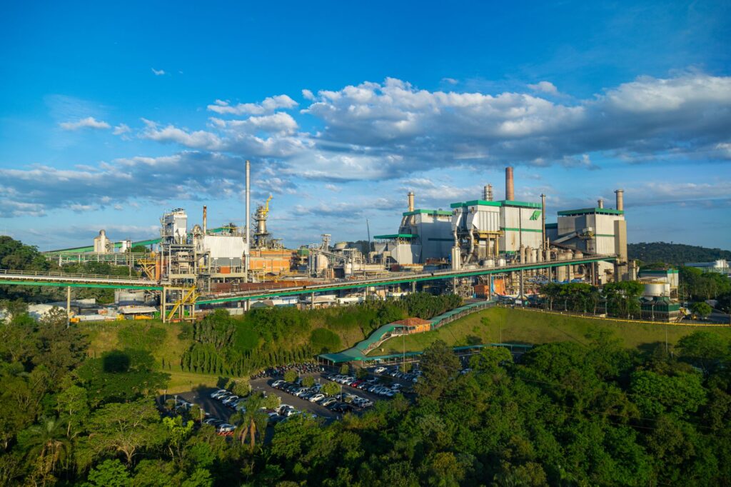 Vista aérea de uma fábrica moderna no Brasil, com painéis solares no telhado e áreas verdes ao redor, simbolizando inovação e sustentabilidade industrial.