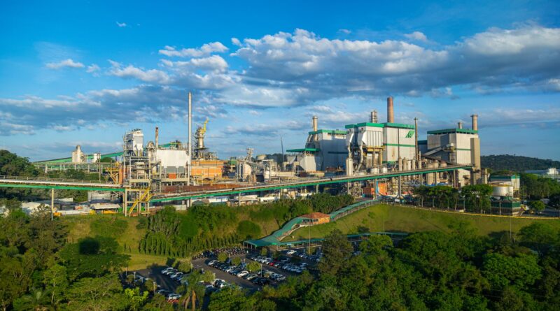 Vista aérea de uma fábrica moderna no Brasil, com painéis solares no telhado e áreas verdes ao redor, simbolizando inovação e sustentabilidade industrial.