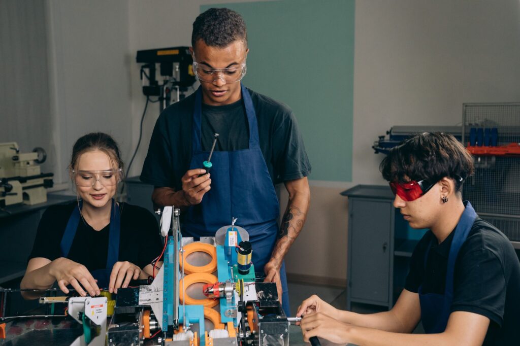 Grupo de pessoas em um ambiente de treinamento, usando computadores e interagindo, simbolizando a requalificação profissional para o futuro do trabalho.