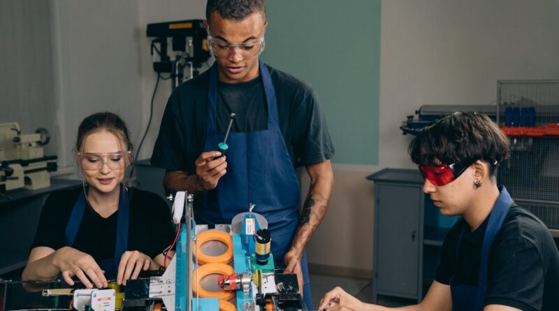 Grupo de pessoas em um ambiente de treinamento, usando computadores e interagindo, simbolizando a requalificação profissional para o futuro do trabalho.