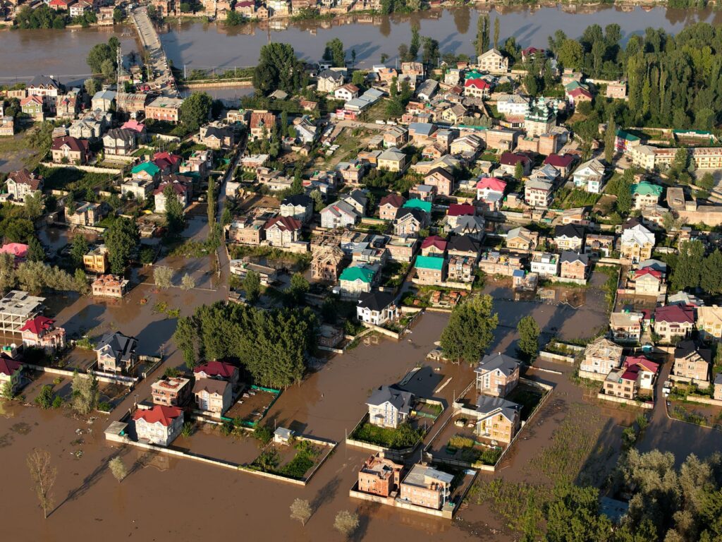 Famílias deslocadas por eventos climáticos extremos no Brasil, com paisagem de seca ou inundação ao fundo