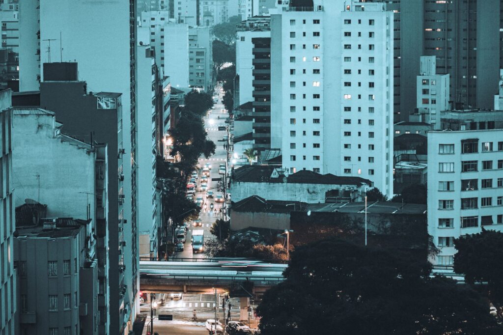 Edifícios modernos e antigos em uma rua movimentada de uma metrópole brasileira, com pessoas caminhando e lojas, simbolizando a transformação urbana e a gentrificação.