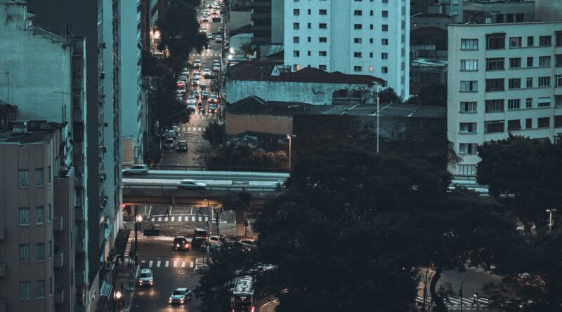 Vista aérea de uma cidade brasileira com tráfego intenso e transporte público em movimento, simbolizando os desafios da mobilidade urbana.