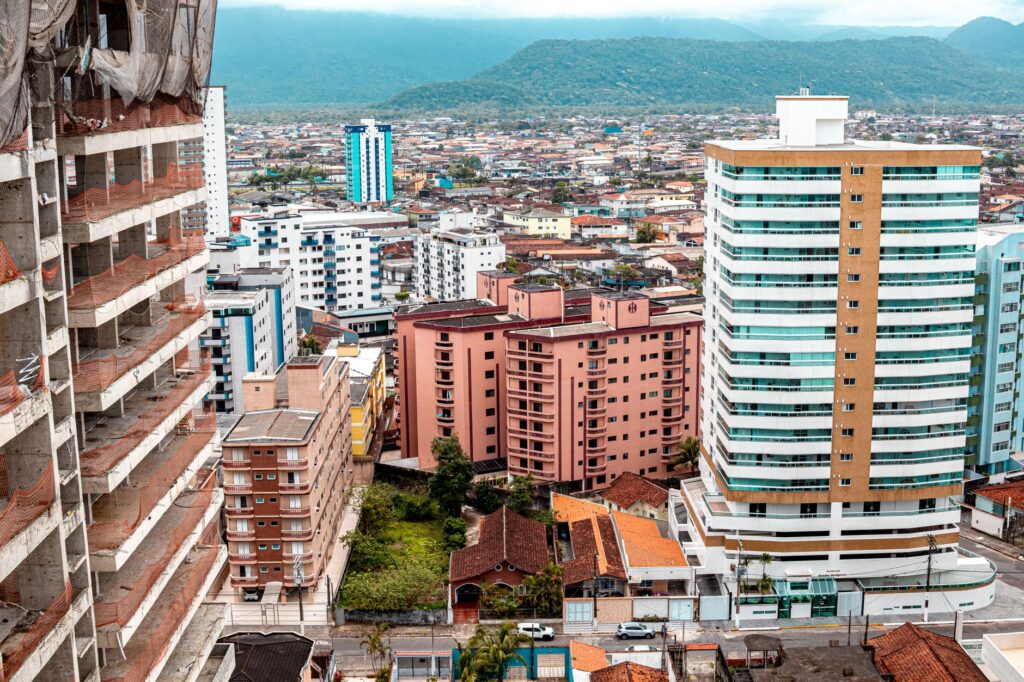 Mãos segurando uma pequena planta brotando de moedas, com turbinas eólicas e painéis solares ao fundo, simbolizando o financiamento verde e o crescimento sustentável no Brasil.