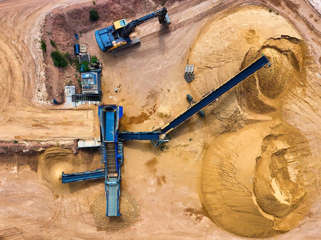Mão segurando minerais brutos com fundo de turbinas eólicas e painéis solares, simbolizando a transição energética