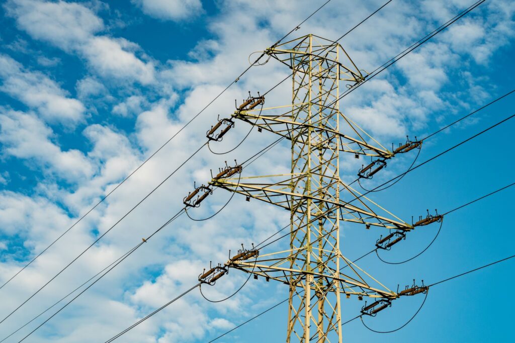 Linhas de transmissão de energia em um cenário com turbinas eólicas e painéis solares, simbolizando a modernização da rede elétrica brasileira para integrar fontes renováveis.