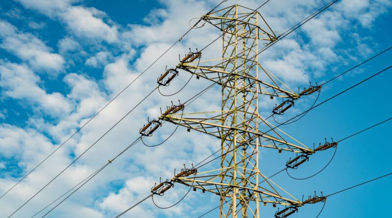 Linhas de transmissão de energia em um cenário com turbinas eólicas e painéis solares, simbolizando a modernização da rede elétrica brasileira para integrar fontes renováveis.