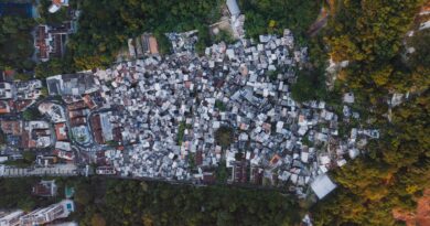Vista aérea de uma área urbana com casas em diferentes estágios de formalização, com sobreposição de um mapa ou planta baixa, simbolizando a regularização fundiária no Brasil.