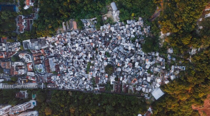 Vista aérea de uma área urbana com casas em diferentes estágios de formalização, com sobreposição de um mapa ou planta baixa, simbolizando a regularização fundiária no Brasil.