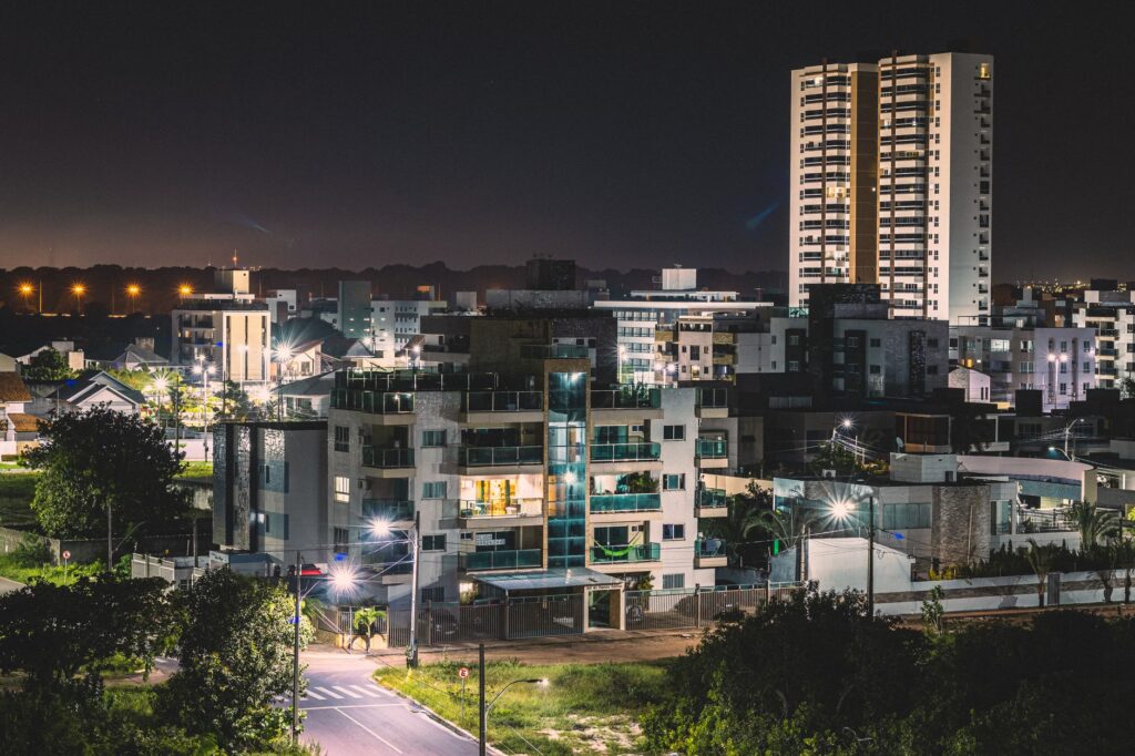 Cena urbana noturna com viatura policial e pessoas, simbolizando a violência nas cidades brasileiras.
