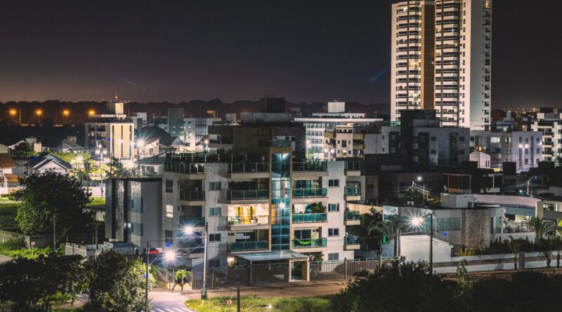Cena urbana noturna com viatura policial e pessoas, simbolizando a violência nas cidades brasileiras.