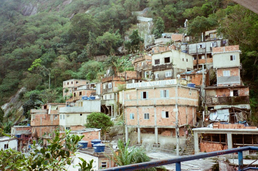 Vista aérea de uma área urbana densamente povoada no Brasil, com contraste entre edifícios formais e assentamentos informais, simbolizando o desafio do déficit habitacional.