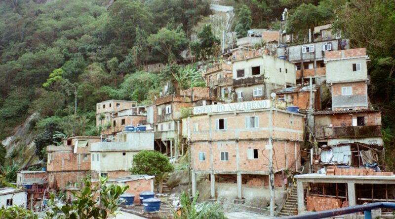 Vista aérea de uma área urbana densamente povoada no Brasil, com contraste entre edifícios formais e assentamentos informais, simbolizando o desafio do déficit habitacional.