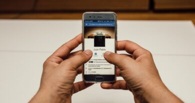 Mãos segurando smartphones com aplicativos de trabalho, com uma balança da justiça ao fundo, simbolizando a judicialização da economia de plataforma.